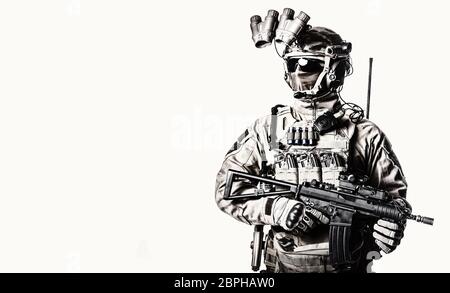 Army elite soldier with hidden behind mask and glasses face, in full tactical ammunition, equipped night vision device, radio headset, armed short bar Stock Photo