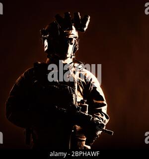 Army elite forces member, modern infantryman with hidden face, in tactical ammunition, equipped radio headset, night vision device mounted on helmet, Stock Photo