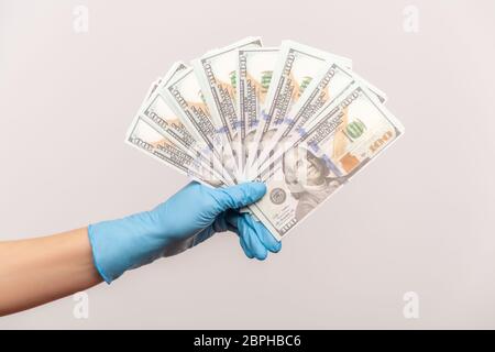 Profile side view closeup of human hand in blue surgical gloves holding and showing fan of american dollar money in hand. indoor, studio shot, isolate Stock Photo