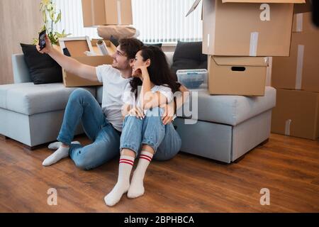 Happy House Owners. Couple Taking Selfie With Smartphone After Moving Into New Home. Stock Photo