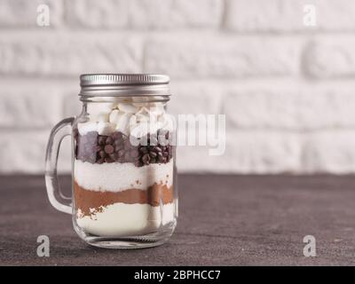 Hot chocolate mix in mason jar. Homemade mix from cocoa, dry milk, sugar, chocolate chips and marshmallows. Christmas and winter holiday budget-friend Stock Photo