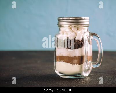 Hot chocolate mix in mason jar. Homemade mix from cocoa, dry milk, sugar, chocolate chips and marshmallows. Christmas and winter holiday budget-friend Stock Photo