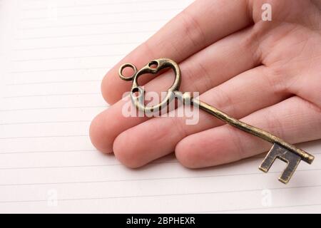 Hand holding a retro styled  golden color   decorative key Stock Photo