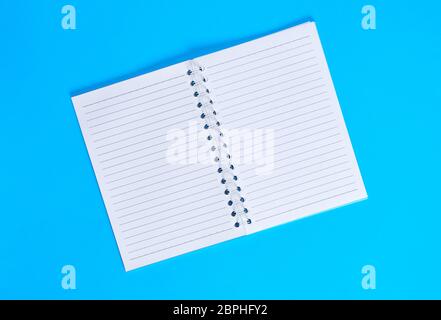 notebook with empty white sheets in line , blue background, top view Stock Photo