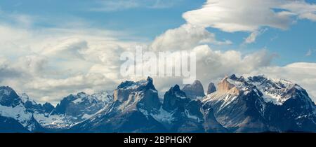Sunshine on the jagged peaks of Cuernos del Paine, with blue sky and white clouds above, after a snow storm, Torres del Paine, Patagonia, Chile Stock Photo