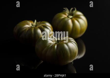 Dark brandywine tomatoes on black background. Stock Photo