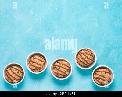 Safe-to-eat raw monster cookie dough in small portion bowl on blue background. Ideas and recipes for kids and toddlers meal. Top view or flat-lay. Cop Stock Photo
