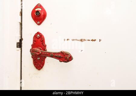 Ancient red door handle on a white broken old door close-up vintage design retro Stock Photo