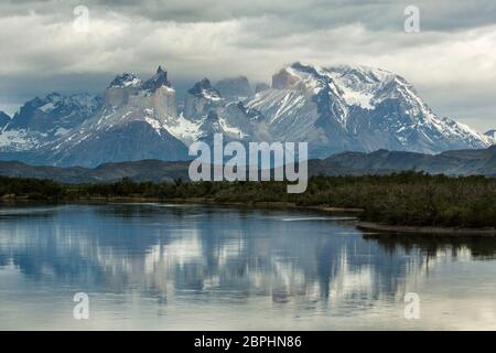 The jagged peaks of Cuernos del Paine, with a stormy sky above, reflected in Lago Pehoe, Torres del Paine National Park, Patagonia, Chile