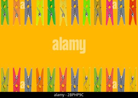 Colorful wooden clothespins on yellow background Stock Photo