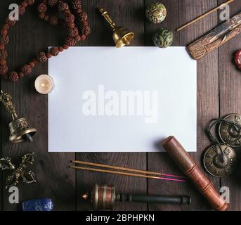 blank white sheet in the middle of religious objects for meditation, relaxation and massage on a brown wooden background Stock Photo