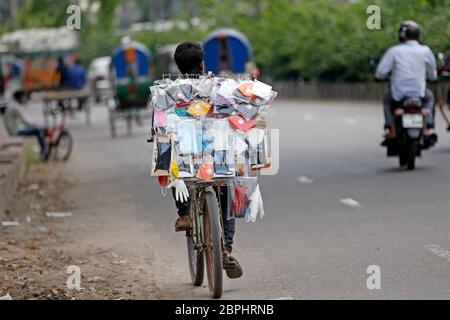 A young boy in afternoon riding a bicycle, from which he sells face masks, gloves and other items that have become essential during the Covid-19 outbr