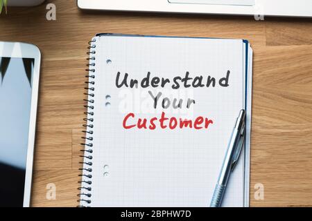 High Angle View Of Understand Your Customer Text Written On Spiral Notepad With Pen Stock Photo