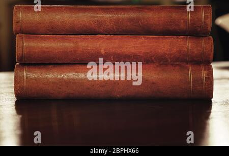 Stack of three old vintage brown leather hardcover books on table Stock Photo