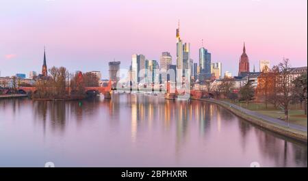 Panoramic view of business district with skyscrapers and mirror reflections in the river at pink sunrise, Frankfurt am Main, Germany Stock Photo