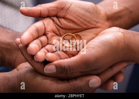 Man And Woman's Hand With Pair Of Golden Engagement Rings Stock Photo