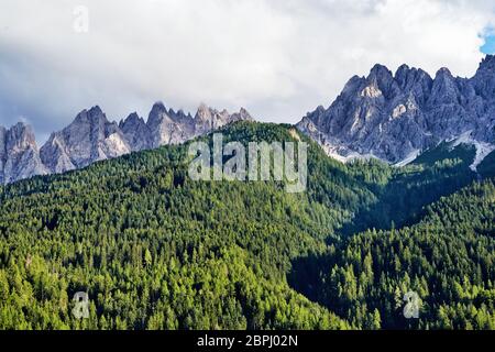 Dolomites mountains in warm season. Green forest on foreground. Italy beauties Stock Photo