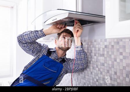 Handyman Checking Kitchen Extractor Filter With Multimeter In Kitchen Stock Photo