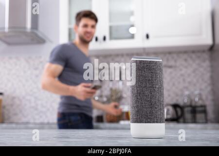 Close-up Of Wireless Speaker In Front Of Man Cutting Vegetables In Kitchen Stock Photo