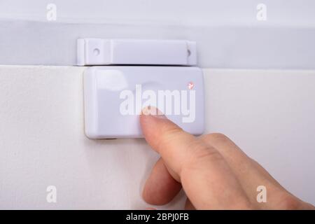 Close-up Of A Person's Finger Pressing Security System Door Sensor Stock Photo