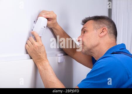 Close-up Of Male Electrician Installing Security System Door Sensor On Wall Stock Photo