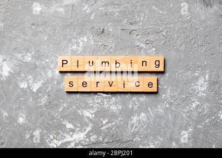 Plumbing service word written on wood block. Plumbing service text on cement table for your desing, concept. Stock Photo