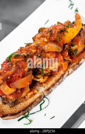 portuguese caldeirada de peixe spicy tomato onion and peppers fish stew on rustic tiborna toast tapas style Stock Photo