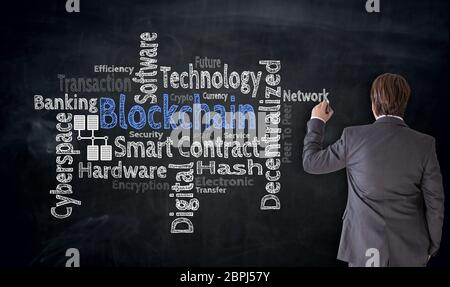 Businessman writes Blockchain cloud on blackboard Concept. Stock Photo