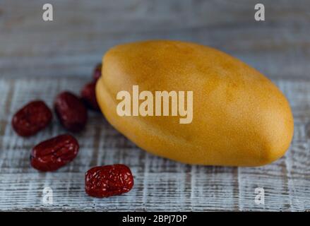 Ripe yellow mango fruit on wooden surface with dates Stock Photo