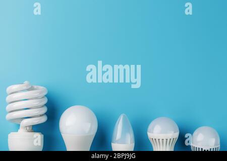 Energy-Saving light bulbs are arranged in a row on a blue background, top view. Progress of led lamps. Stock Photo