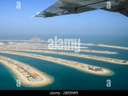 Flying over the island palm tree in Dubai. The view from the window of a passenger plane during the flight, the wing of the turbine engine of the airc Stock Photo