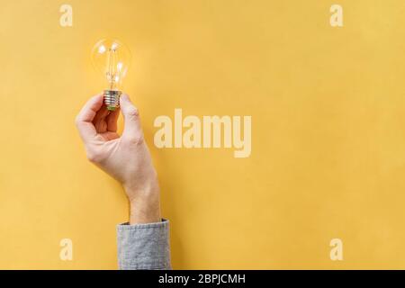 Man's hand holding retro lamp in his hand on yellow background Stock Photo