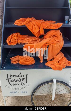 Wet Beach towels stacked in shelves in a rack fitted on a tricycle, an original idea from a tropical resort Stock Photo