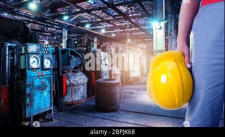 Closeup of worker man with yellow helmet on Industrial zone background, manufacturing facility. Concept of Safe labor in the enterprise. Stock Photo