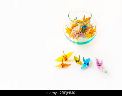 Small origami birds paper on white background and a glass jar filled with origami birds paper, top view, be free concept Stock Photo