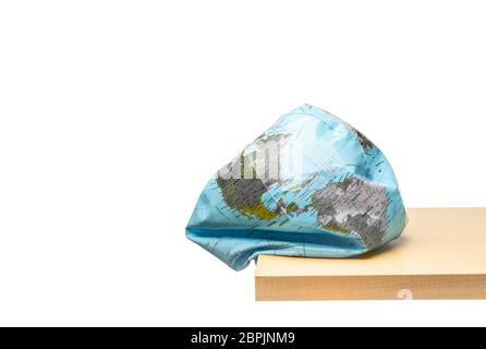 Flattening globe earth at the edge of wood table on white background, Environmental damage concept Stock Photo