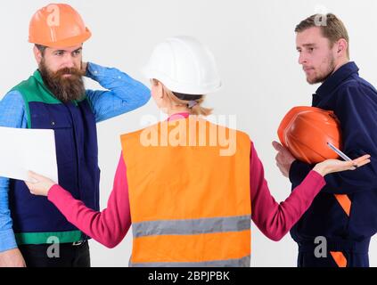 Female engineer talking with two builders with pensive faces in uniform and hard hats, isolated on white background Stock Photo