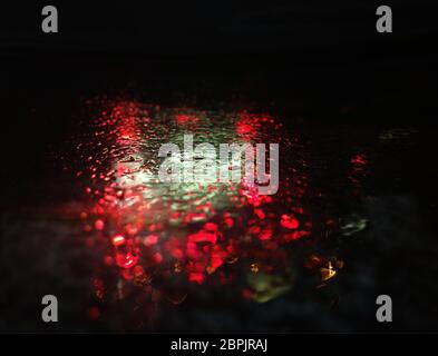 Dramatic red and green raindrops on rainy surface background Stock Photo
