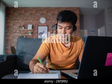 Asian businessmen is using notebook computers and wear headphones for online meetings and working from home. Stock Photo