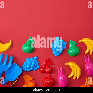 plastic childrens toys in the form of fruit and a bucket on a red background Stock Photo