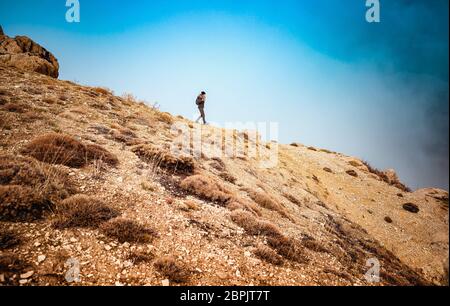 Woman hiking along beautiful mountains, active female with backpack traveling along high mountaing, enjoying vacation and freedom Stock Photo