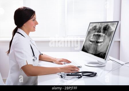 Female Doctor Looking At Teeth X-ray On Computer Over Desk In Clinic Stock Photo