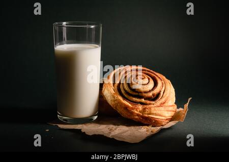 still life, cinnamon roll and a glass of milk on a dark background Stock Photo