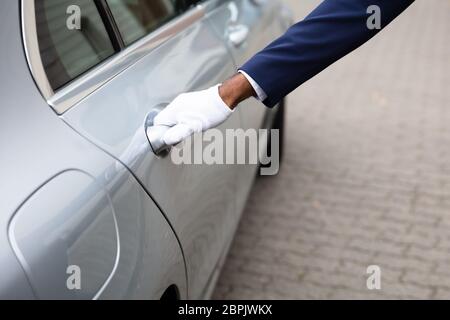 Valet's Hand Opening Grey Car Door On Street Stock Photo