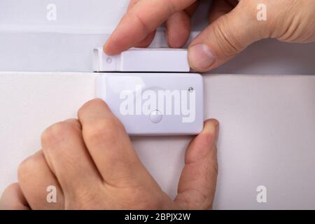 Close-up Of Person's Hand Fixing Security System Door Sensor Stock Photo