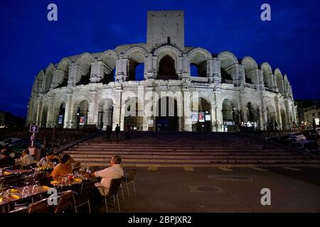 The night view Arles Amphitheatre and medieval tower with outdoor cafe in foreground.Arles.Bouches-du-Rhone.France Stock Photo