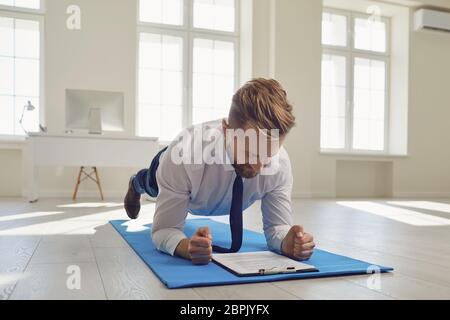 Businessman doing abs strap exercises while lying in the office. Stock Photo