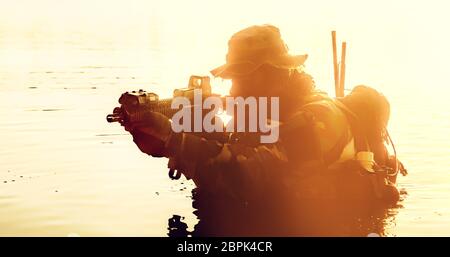 Silhouette of special forces with rifle in action during river raid in the jungle waist deep in the water Stock Photo