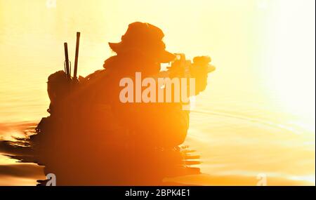 Silhouette of special forces with rifle in action during river raid in the jungle waist deep in the water Stock Photo