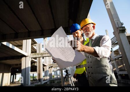 Male architects analyzing blueprint at construction site Stock Photo